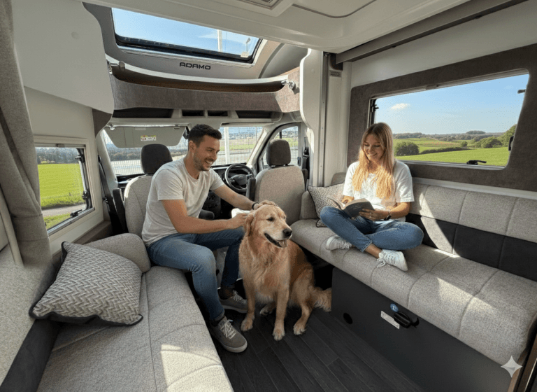A couple and their dog relaxing inside a dog-friendly Why Knott Hire campervan